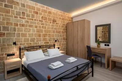 a bedroom with a bed and a brick wall at Mulberry Apartments in Rhodes Town