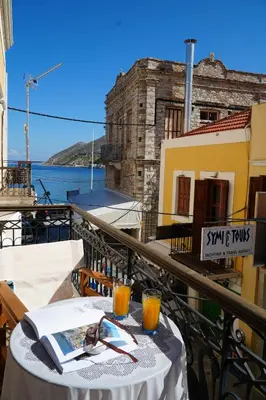 a table on a balcony with a view of the water at Antoni's Symi Home in Symi