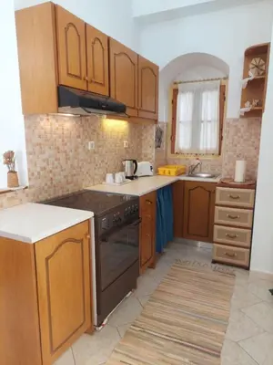 a kitchen with wooden cabinets and a stove top oven at Antoni's Symi Home in Symi