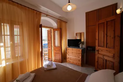 a bedroom with a bed and a tv and a window at Antoni's Symi Home in Symi
