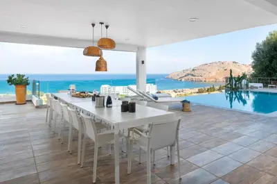 a dining room with a table and chairs and a view of the ocean at Luxury Villa Oceania Lindos with Private Infinity Pool in Líndos