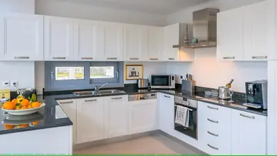 a kitchen with white cabinets and a bowl of fruit on the counter at Luxury Villa Oceania Lindos with Private Infinity Pool in Líndos