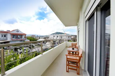 a balcony with two chairs and a table at Elli Garden View in Kremasti