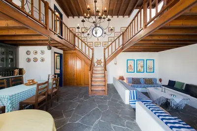 a dining room with a staircase and tables and chairs at Litsa Holiday Home in Kalathos