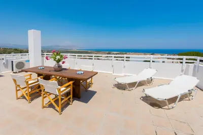 a patio with a wooden table and chairs on a roof at Litsa Holiday Home in Kalathos