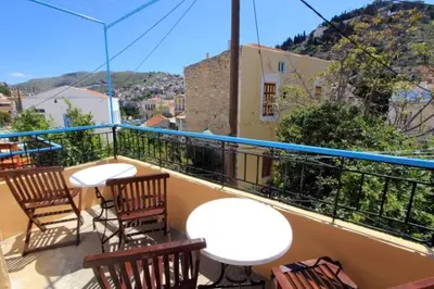 a balcony with chairs and tables on a balcony at Symi Center Hotel in Symi