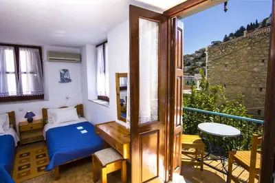 a bedroom with a bed and a balcony with a table at Symi Center Hotel in Symi