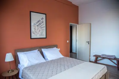 a bedroom with a bed with an orange wall at mandala central apartment in Rhodes Town