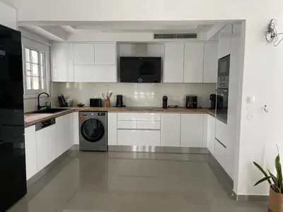 a kitchen with white cabinets and a washer at Luminous Home City Rhodes in Rhodes Town