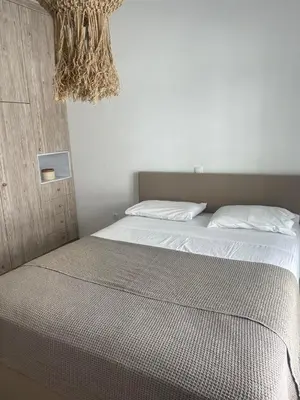 a bedroom with a bed with white sheets and a chandelier at Luminous Home City Rhodes in Rhodes Town