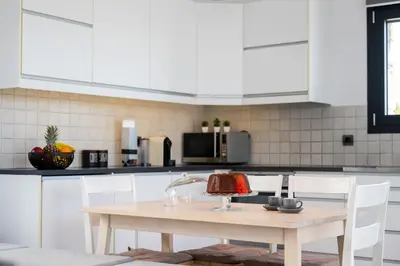 a kitchen with a wooden table and white cabinets at Prasonisi Villas in Kattavía