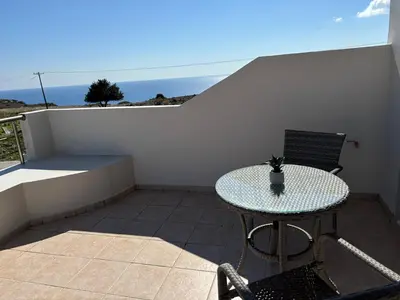 a table and chairs on a balcony with the ocean at Erato Sea View Villa in Koskinou