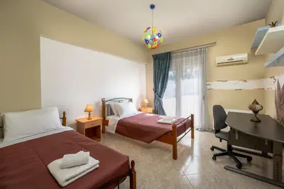 a bedroom with two beds and a desk and a window at Stavroulas Amazing House in Phanaes