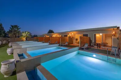 a villa with a swimming pool at night at M&B Luxury Suites Charaki in Haraki