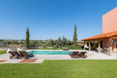 a backyard with a pool and chairs and a house at Villa Sephora in Faliraki