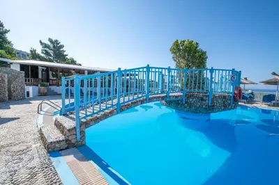 a bridge over a pool with blue water at Ageri & Tritonis Luxury Apartments in Pefki Rhodes