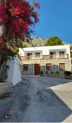a house with a balcony and a tree with red flowers at Ageri & Tritonis Luxury Apartments in Pefki Rhodes