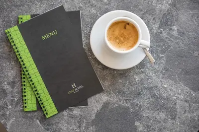 a cup of coffee next to a book and a ruler at Lime Hotel Faliraki in Faliraki