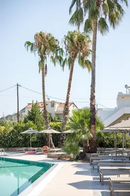 a swimming pool with chairs and palm trees at Lime Hotel Faliraki in Faliraki