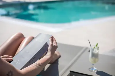a woman laying on a table reading a book at Lime Hotel Faliraki in Faliraki