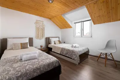 two beds in a room with a chair and a window at Kostas Nest in Ialyssos