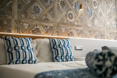 a bed with blue and white pillows and a wooden wall at Paradise City Apartment in Rhodes Town