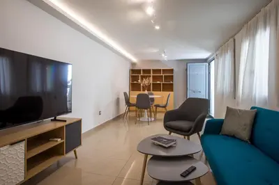 a living room with a blue couch and a tv at Paradise City Apartment in Rhodes Town