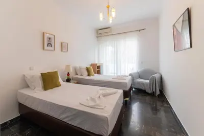 a room with two beds and a chair in it at Eln's Sunlit Apartment in Rhodes Town