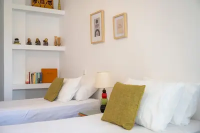 a bedroom with two white beds and a couch at Eln's Sunlit Apartment in Rhodes Town