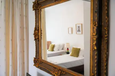 a mirror reflecting a bedroom with a bed and a couch at Eln's Sunlit Apartment in Rhodes Town