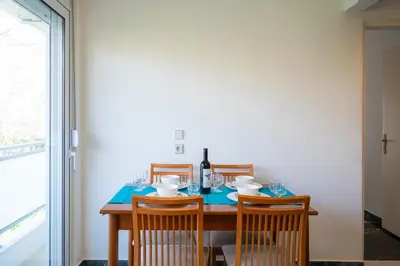 a dining room table with four chairs and a bottle of wine at Eln's Sunlit Apartment in Rhodes Town