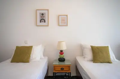 two beds in a room with a lamp on a table at Eln's Sunlit Apartment in Rhodes Town