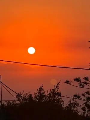 an orange sunset over the water with a telephone wire at House of Happiness Rhodos in Kritinía