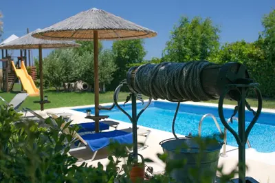 a swimming pool with an umbrella and some chairs and a swimming pool at Villa Euphoria in Gennadi
