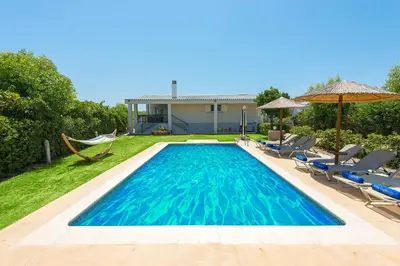 a swimming pool with chairs and a house at Villa Euphoria in Gennadi