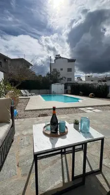 a bottle of wine on a table next to a pool at ''TSI TSI' traditional home & private Pool' in Kalithies