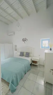 a white bedroom with a bed and a couch at ''TSI TSI' traditional home & private Pool' in Kalithies