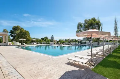 a swimming pool with chairs and an umbrella at Afandou Bay Village Resort Hotel in Afantou