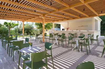 a patio with tables and chairs and a bar at Afandou Bay Village Resort Hotel in Afantou