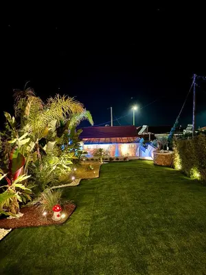 a garden at night with a building and lights at City Compass Sunset Villa in Rhodes Town