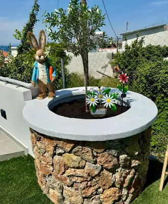 a statue of a rabbit sitting in a flower garden at City Compass Sunset Villa in Rhodes Town