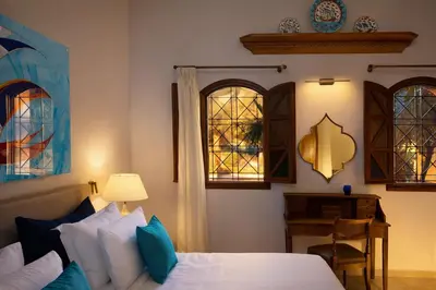 a bedroom with a bed and two windows at Palazzo Navarone in Líndos