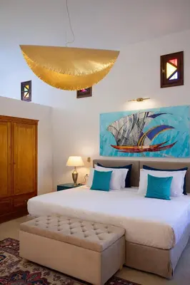 a bedroom with a large white bed with a couch at Palazzo Navarone in Líndos