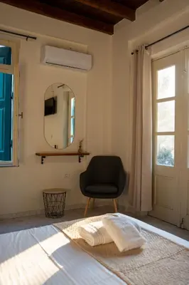 a bedroom with a chair and a mirror and a bed at Vavana Studios in Symi