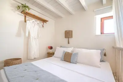 a white bedroom with a bed and a window at Melenia House in Koskinou