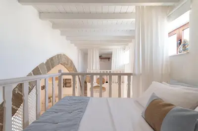 a white bedroom with a bed on a staircase at Melenia House in Koskinou