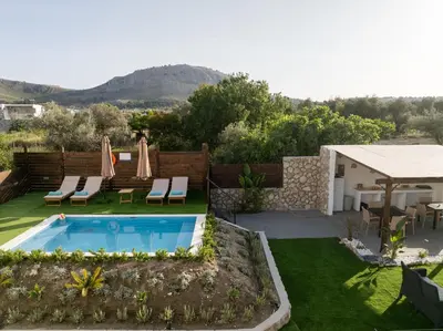 a garden with a swimming pool and a table and chairs at Kathy's apartments in Archaggelos in Archangelos