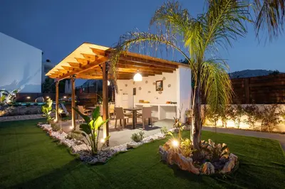 a backyard with a house with a table and a palm tree at Kathy's apartments in Archaggelos in Archangelos