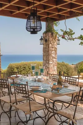 a table with glasses and chairs on a patio at Villa Russelia in Kalavárda