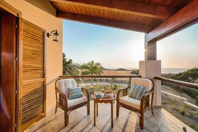 a balcony with a table and chairs and a view of the ocean at Villa Russelia in Kalavárda